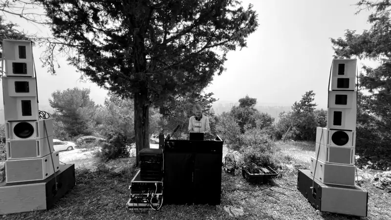 A DJ booth on a hillside, between two sound rigs